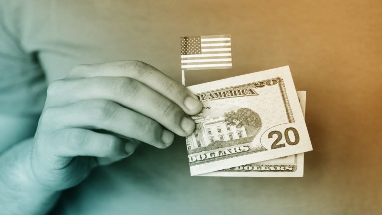 Homme tenant dans sa main un mini drapeau américain entouré d'un billet de 20 dollars