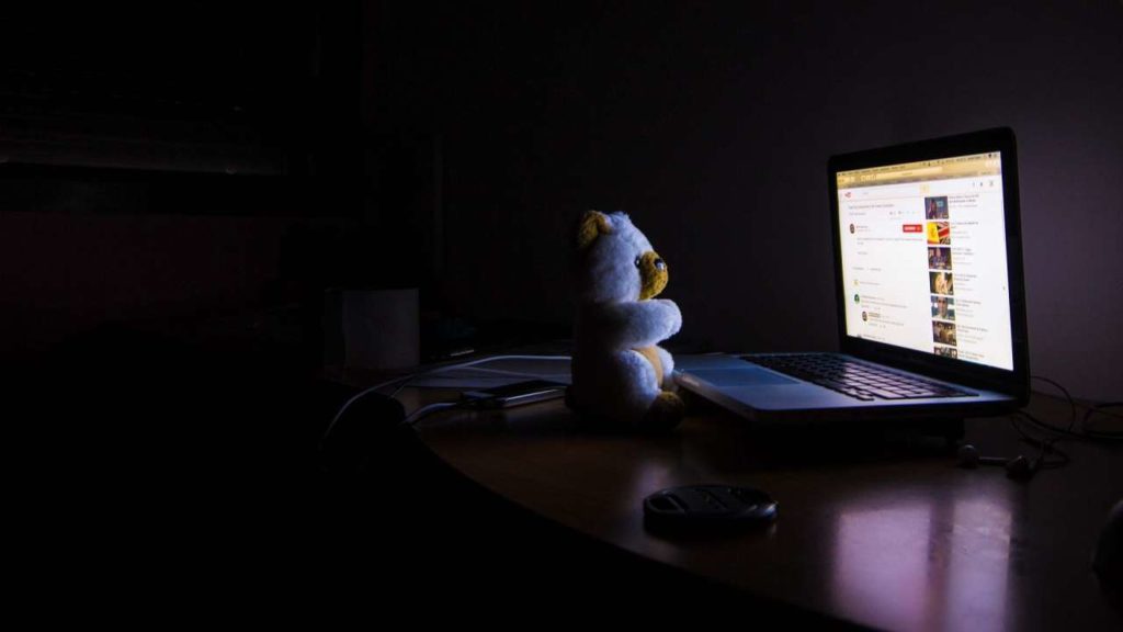 Ours en peluche dans le noir devant un écran d'ordinateur