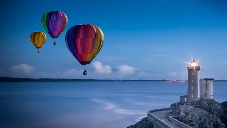 Trois mongolfières se dirigeant vers un phare