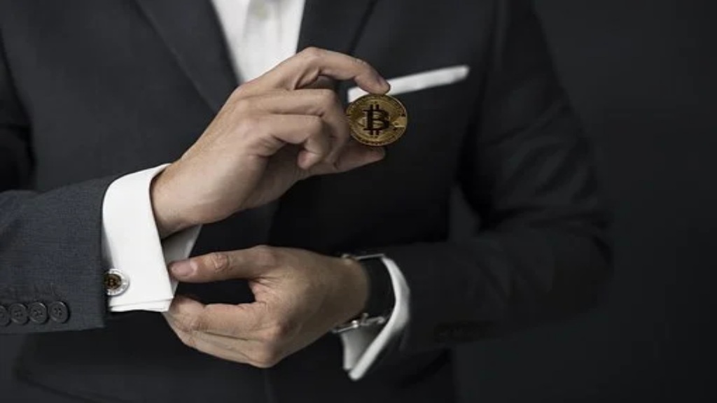 Homme en costume tenant un jeton de Bitcoin