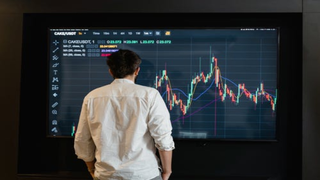 Un homme devant un grand écran de trading